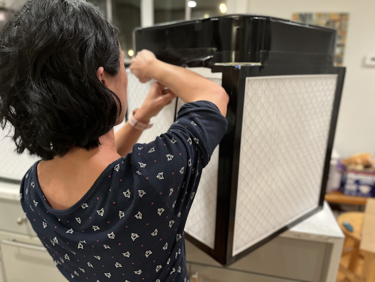 a woman tapes together a cube measuring 2 feet on a side