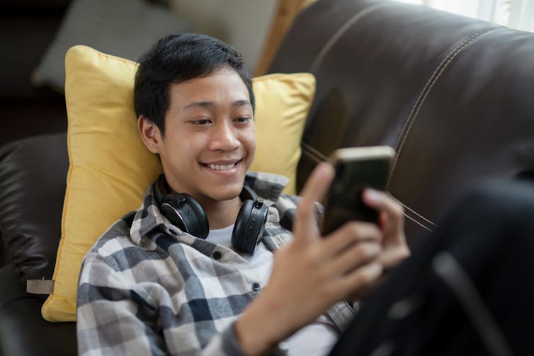 Young man lying on couch and looking through his phone.