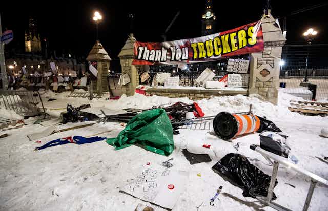Garbage is laid out on the snow in front of a big sign that says Thank You TRUCKERS