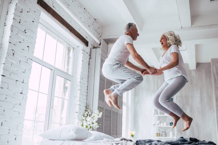 older couple jump on bed with joy