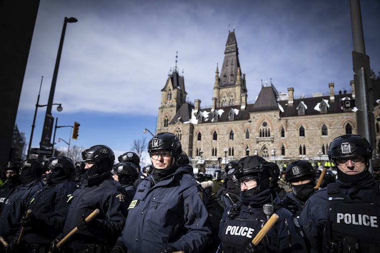 Police line up in front of Parliament Hill buildings.