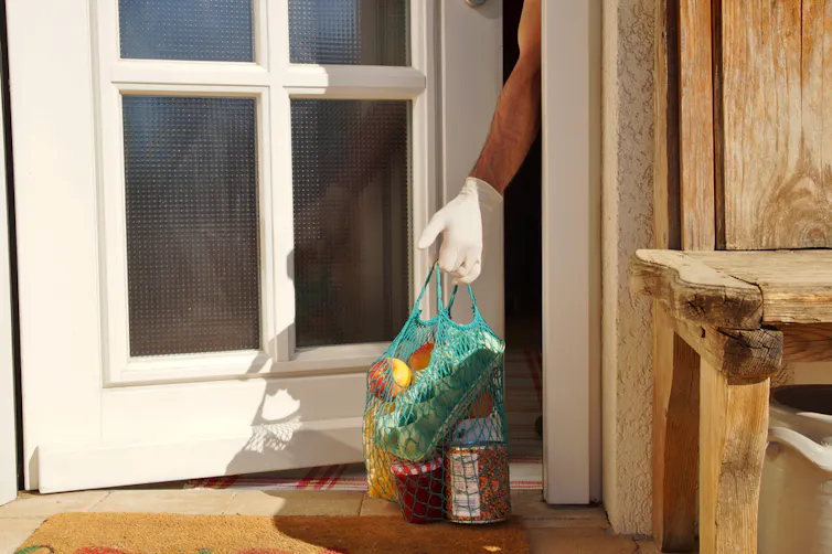 A self-isolating person picking up groceries delivered to their porch