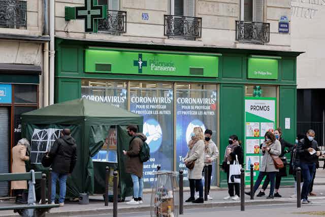 Des gens font la queue devant une pharmacie parisienne