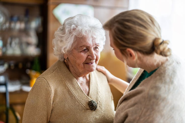 An elderly woman is comforted by a younger woman.