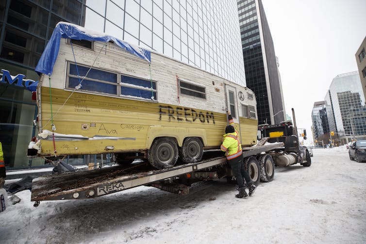 A person is seen securing a camper van that says 'Freedom'