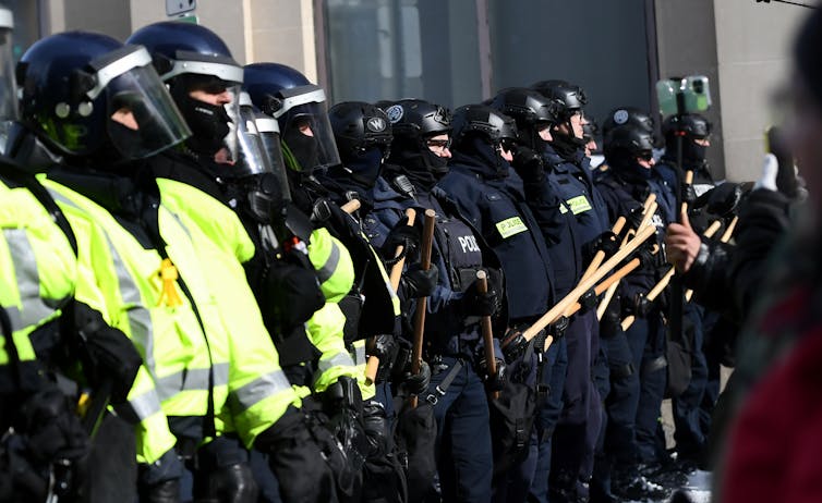 A line of armoured police, some holding batons.