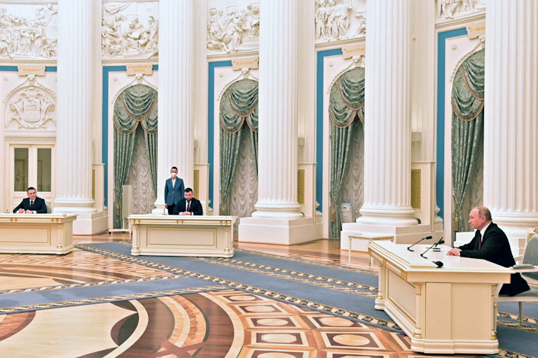 Russian President Putin signs documents in a very grand room.