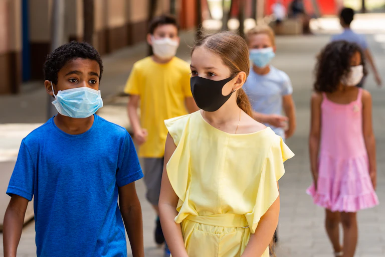 A row of school children walking while wearing face masks