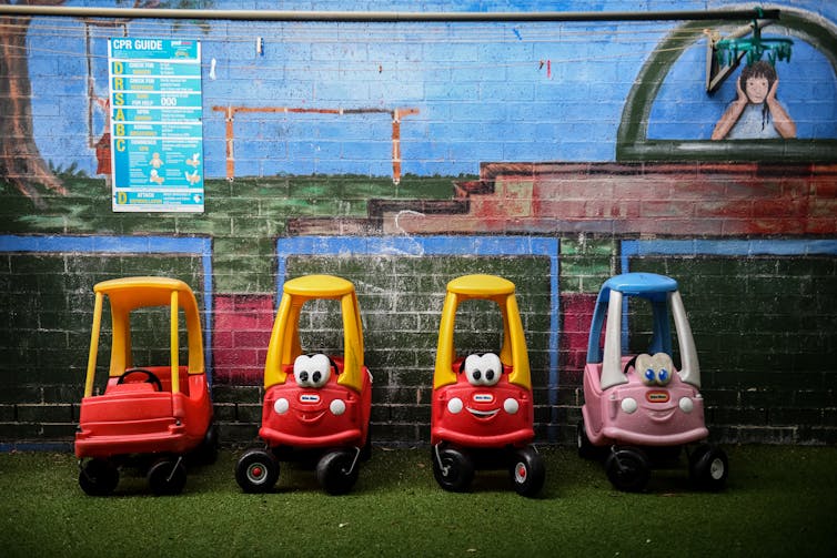 Row of children's toy buggies lined up against a wall.