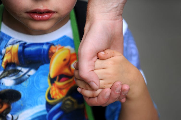 Child holding the hand of an adult.