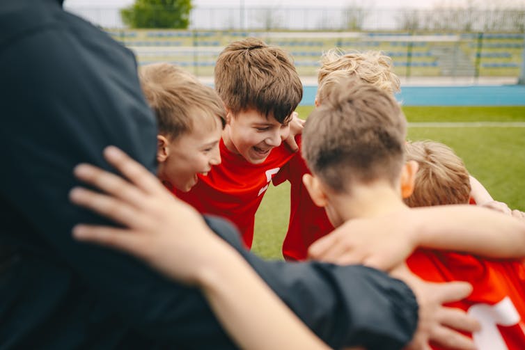 Children in a huddle on the middle of a sport ground