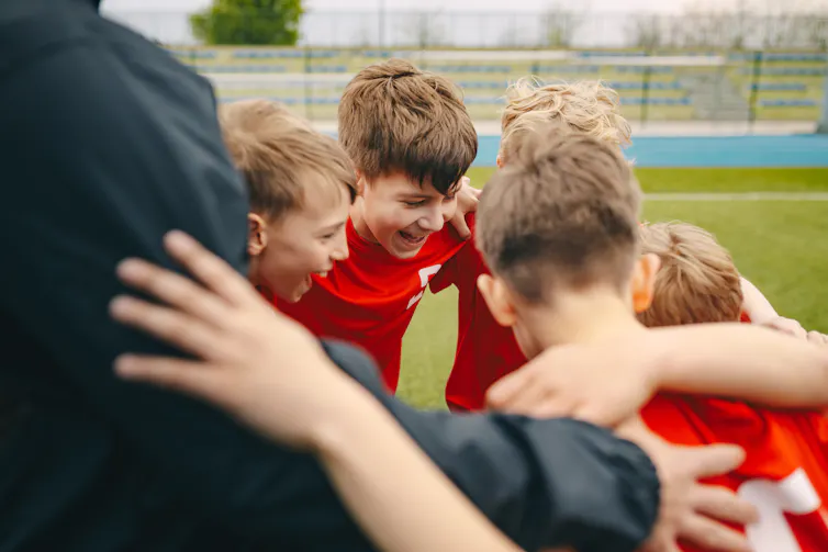 Children in a huddle on the middle of a sport ground