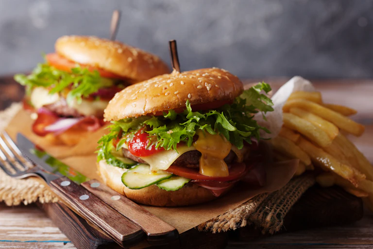 Burgers, fries and a knife and fork on a platter.