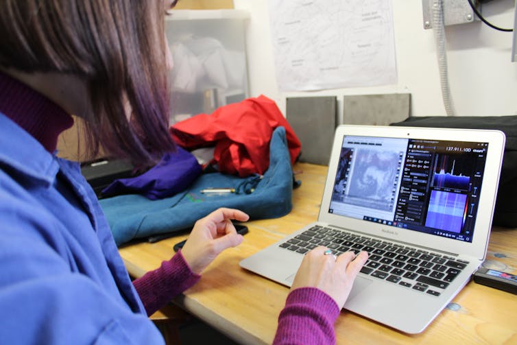 An over-the-shoulder view of someone editing satellite images on a laptop.