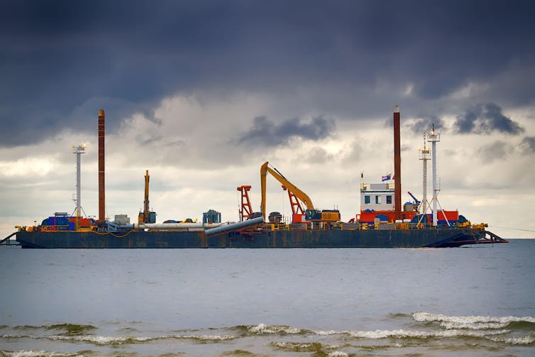 A colourful ship takes part in laying a gas pipeline beneath the seabed.