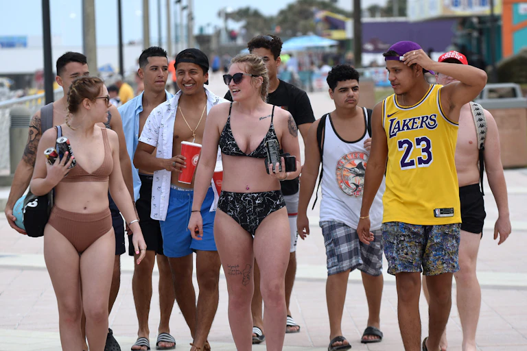 A group of college students walk across the beach.