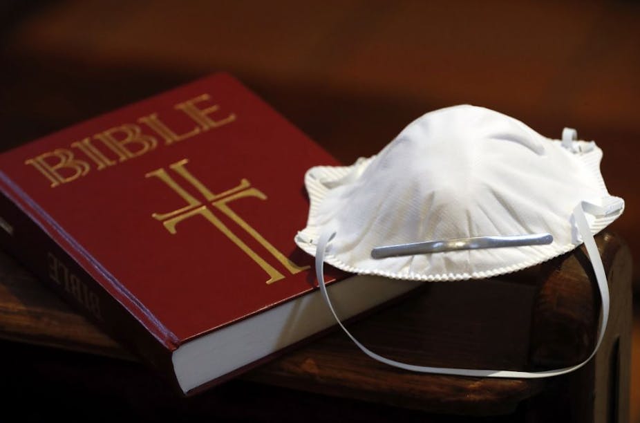 A Bible next to a disposable face mask.
