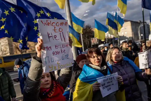 People hold signs - one says 'Welcome to Hell' - and chant slogans during a protest outside the Russian Embassy on February 22, 2022 in Kyiv, Ukraine.