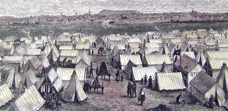 A town of tents against a backdrop of hills in the far distance.