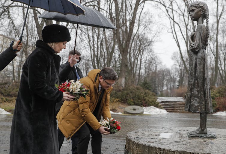 Liss Truss stands next to the statue of a little girl as a memorial to the the 1930s Ukraine famine