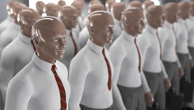 An army of identical humanoid mannequins with shiny, bald plastic heads wearing collared shirts and red ties