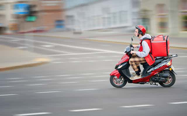 Food courier on a red scooter.
