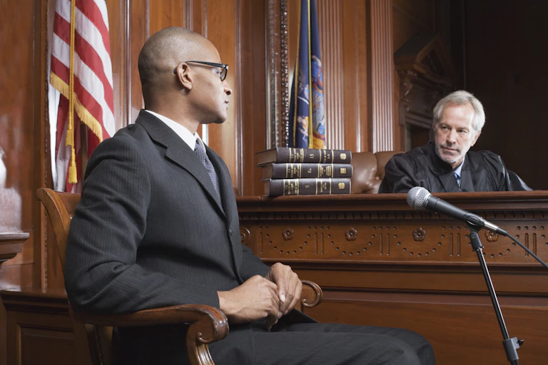 A judge skeptically looks at a man seated opposite his bench.