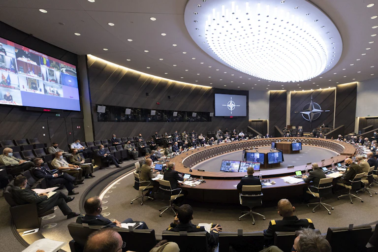 People gather around a large conference room with a circular table in the center