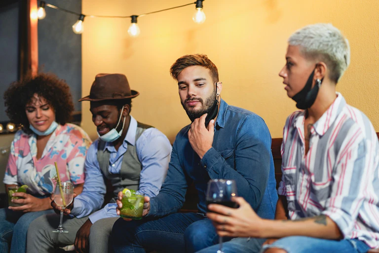 A group of people with drinks and masks pulled down around their chins.