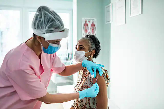 Close-up of a senior woman getting vaccinated by a female doctor.