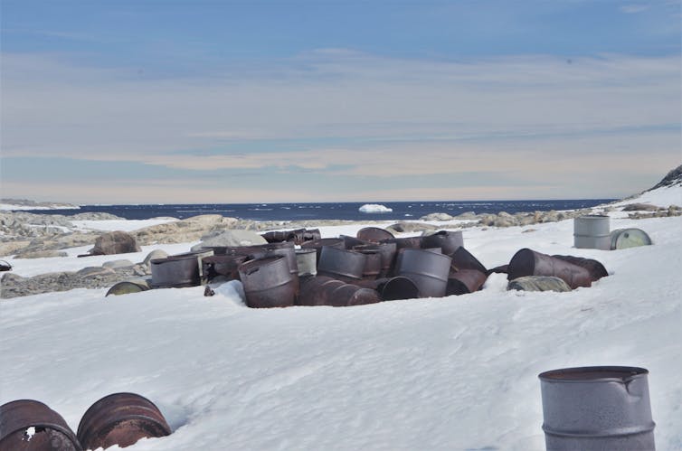 Rusted oil barrels partly buried in the snow at the abandoned Wilkes station in Antarctica.