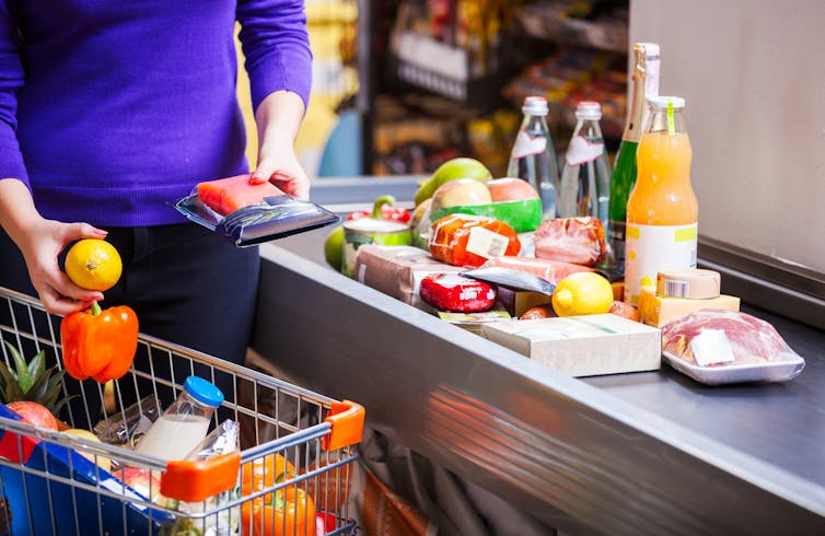 A woman at a supermarket till with food items.