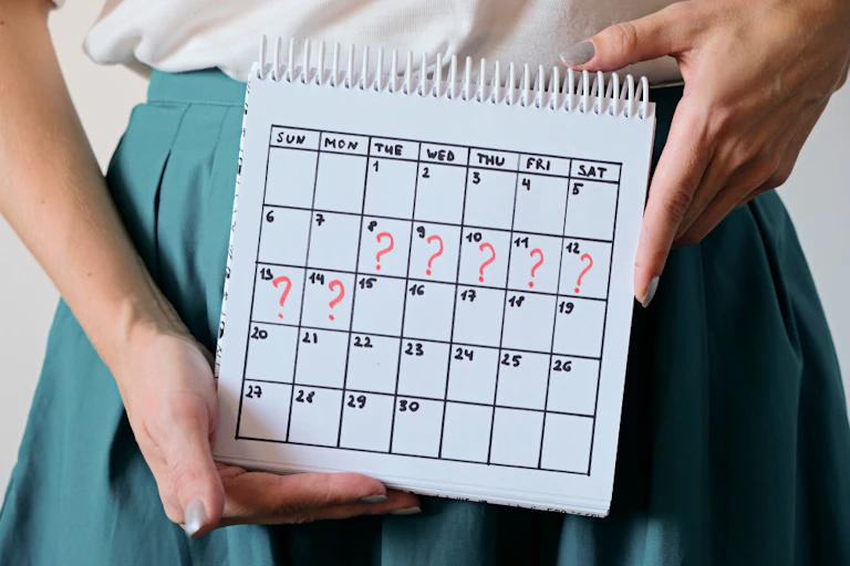 A woman holding a calendar with certain days annotated with question marks