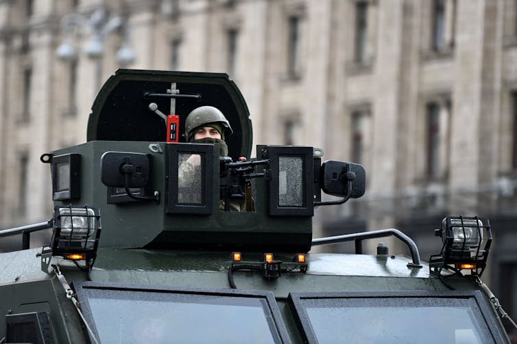 Um soldado usando um capacete espreita para fora de um tanque.