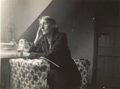 Black and white image of woman looking out of a window.