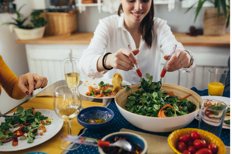 A woman scoops herself up a serving of vegetarian spinach salad.