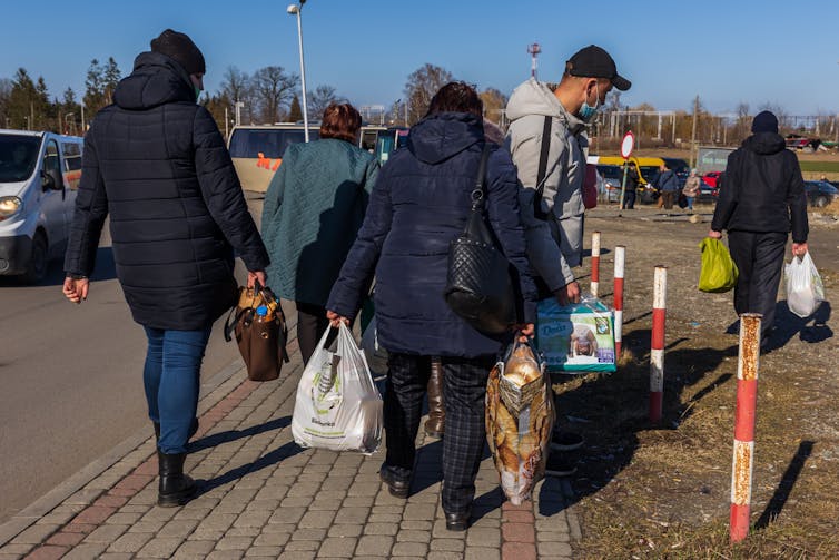 A handful of people dressed in winter coats and carrying bags.