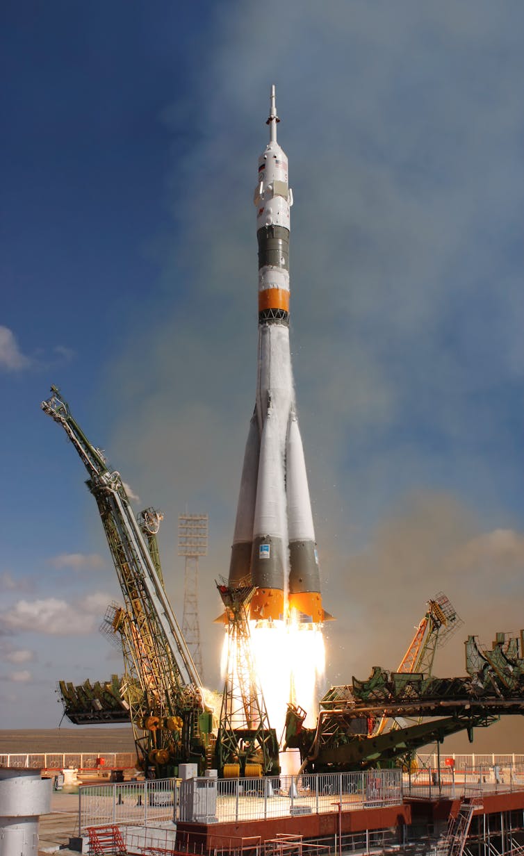 A white Soyuz rocket lifting off from a launch pad.