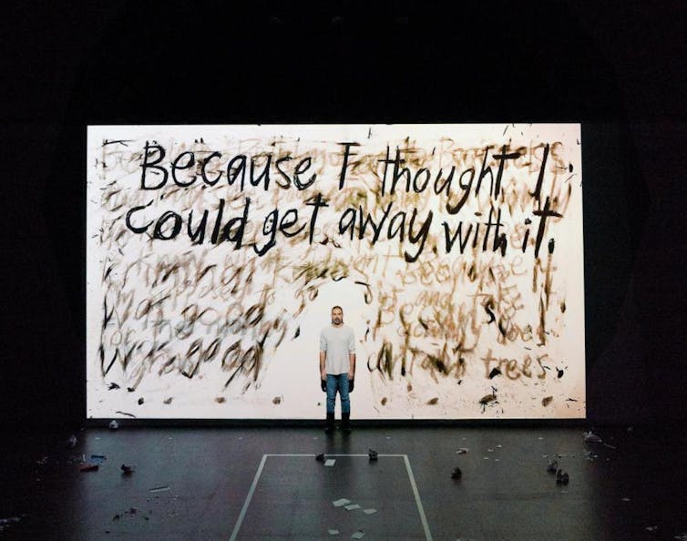 A man stands in front of large handwritten words: Because I thought I could get away with it.