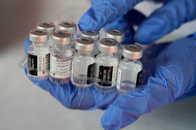 Person holding Pfizer vaccine vials