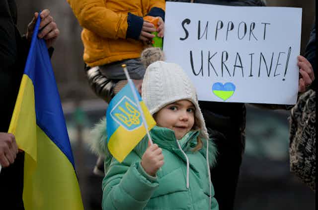 4 year-old, plays with the Ukrainian flag during a protest against the Russian invasion of Ukraine in front of the Ukrainian embassy in Bucharest, Romania