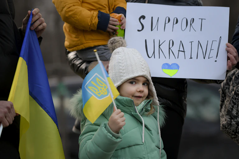4 year-old, plays with the Ukrainian flag during a protest against the Russian invasion of Ukraine in front of the Ukrainian embassy in Bucharest, Romania