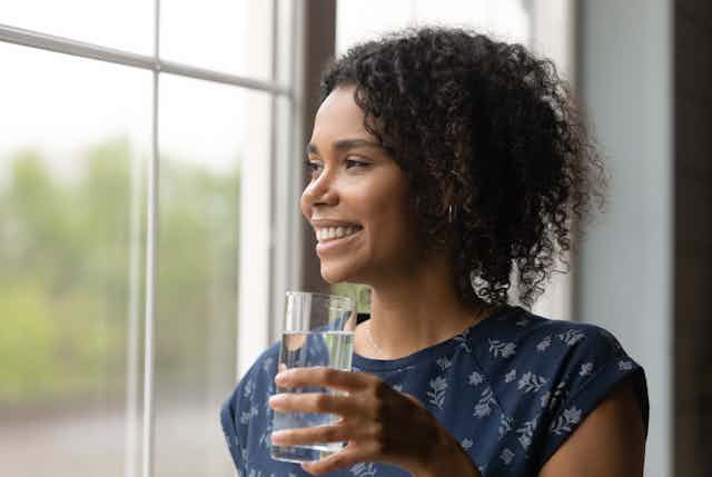 woman smiles and holds glass of water