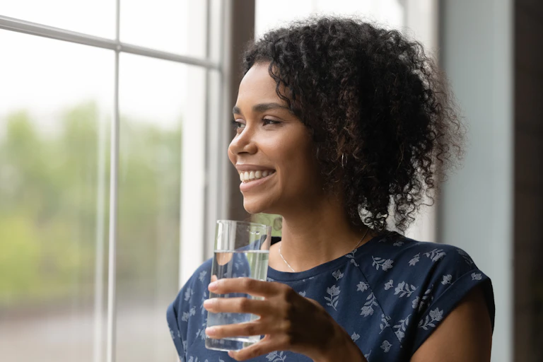 woman smiles and holds glass of water