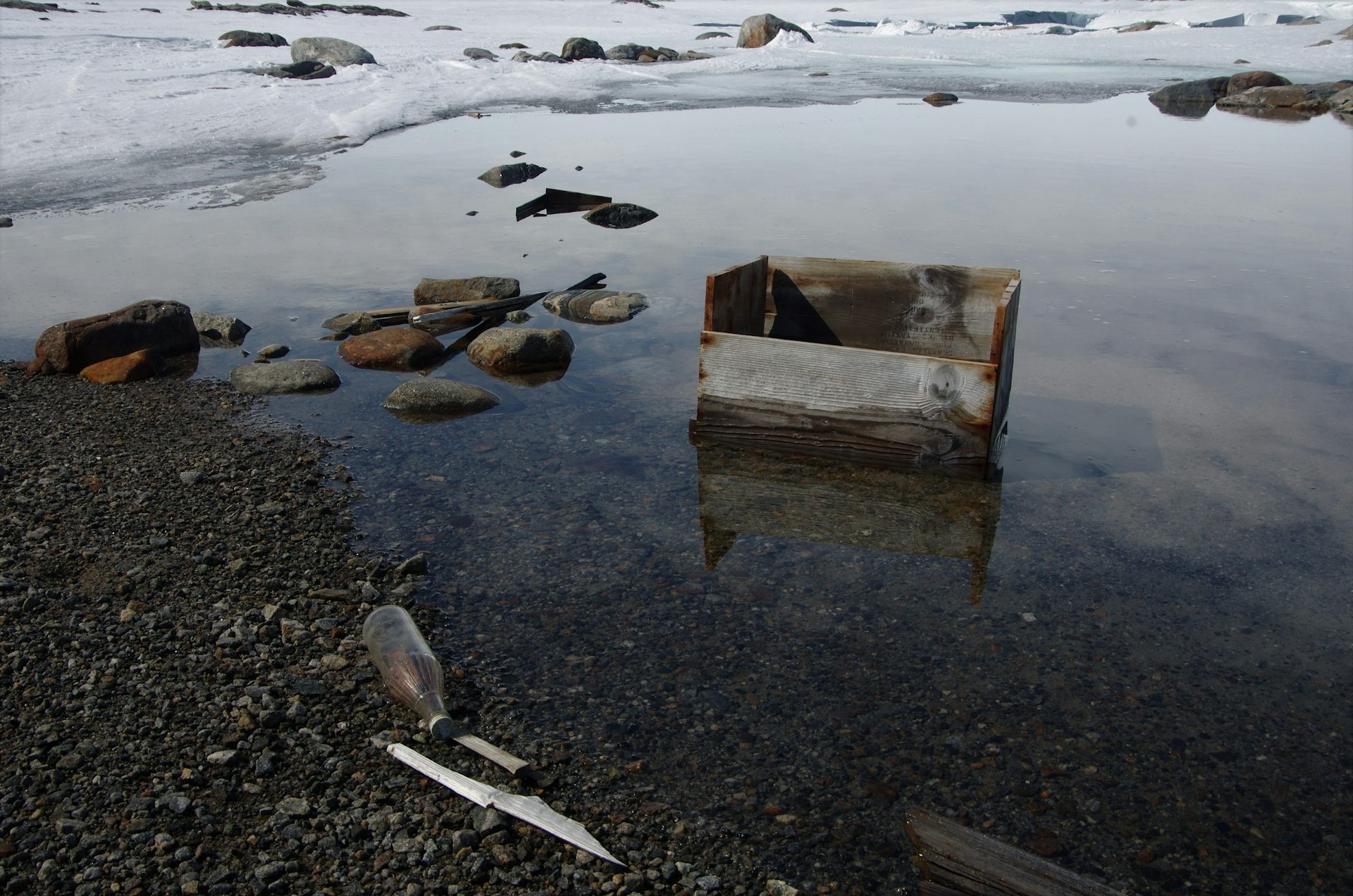 A glass bottle and wooden crate in a melt lake near Wilkes Station