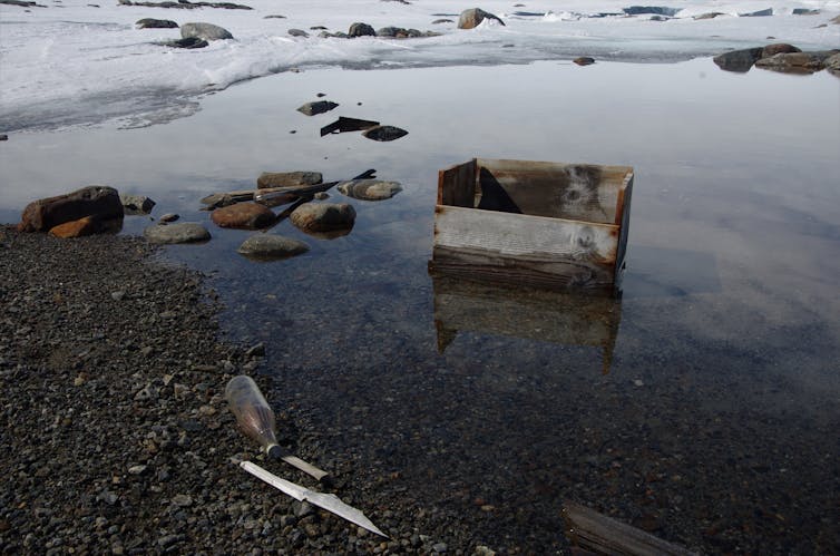 A glass bottle and wooden crate in a melt lake near Wilkes Station