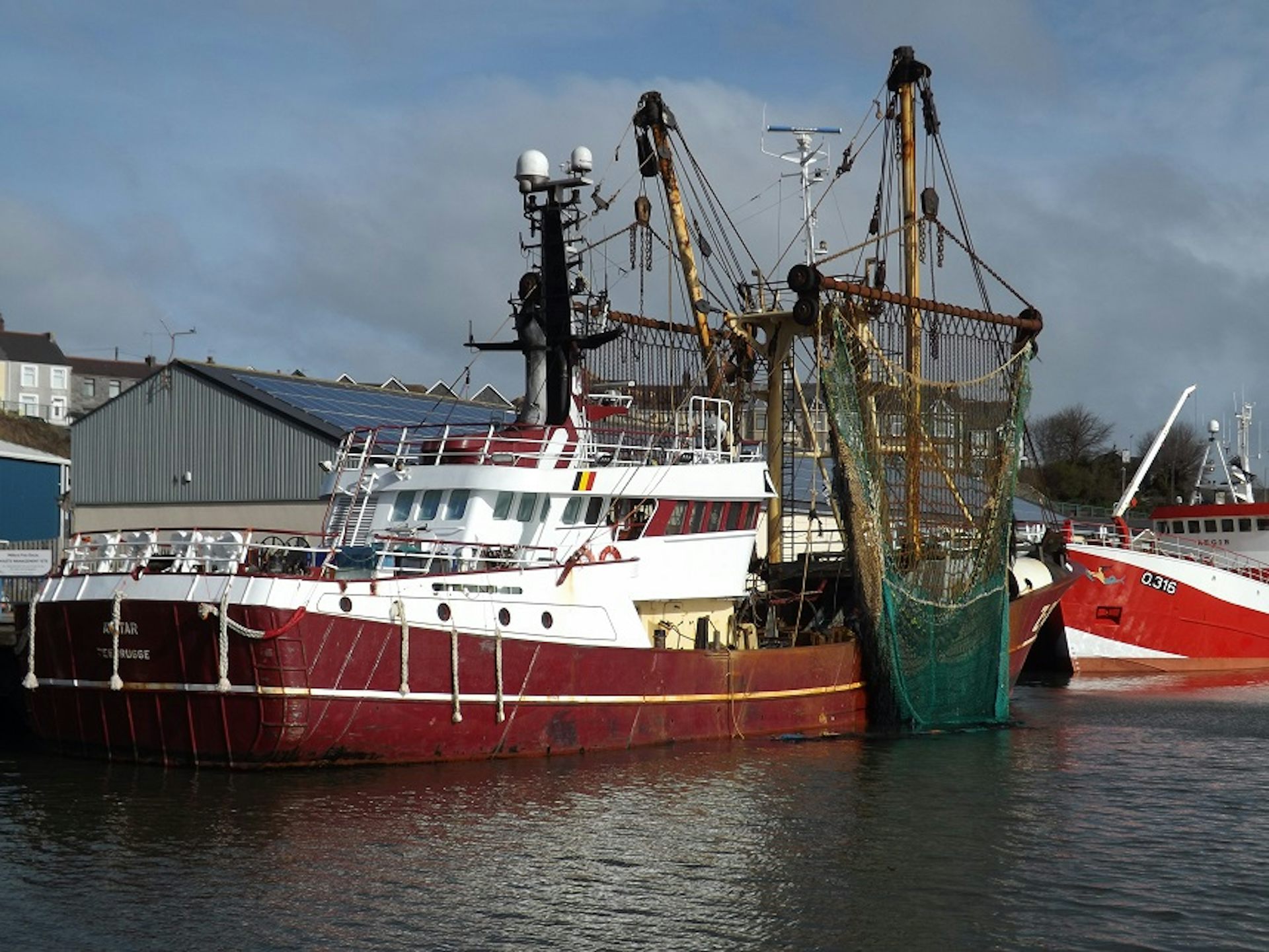A red boat with large fishing equipment.