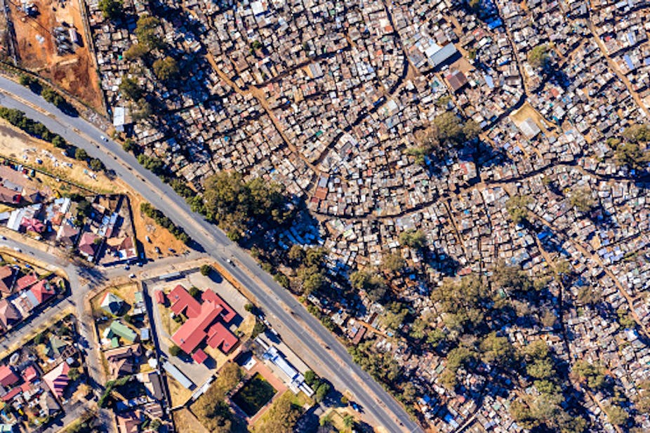 Aerial view of a road separating houses and informal settlements.