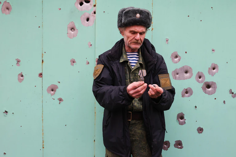 Ukranian male resident stands next to building damaged by shelling.