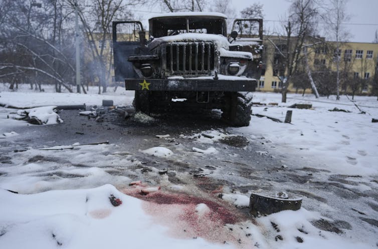 Blood is seen in the snow in front of an armoured vehicle.